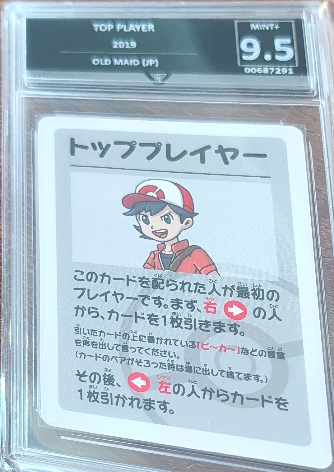 Trading card with a character in a red cap and jacket, encased in protective glass with a grading label.